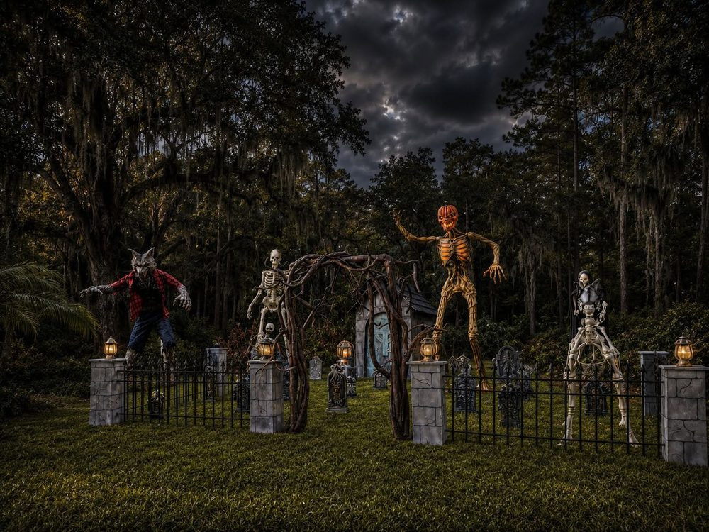 A moonlit graveyard under Spanish moss, with a tall pumpkin-headed figure standing among the headstones
